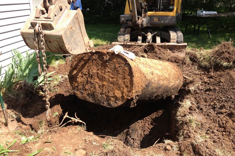 Buried oil tank excavated and lifted from the ground during underground removal on Long Island